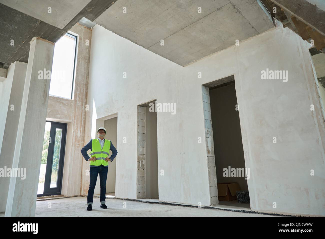 Serious male foreman inspecting a huge unfinished house Stock Photo