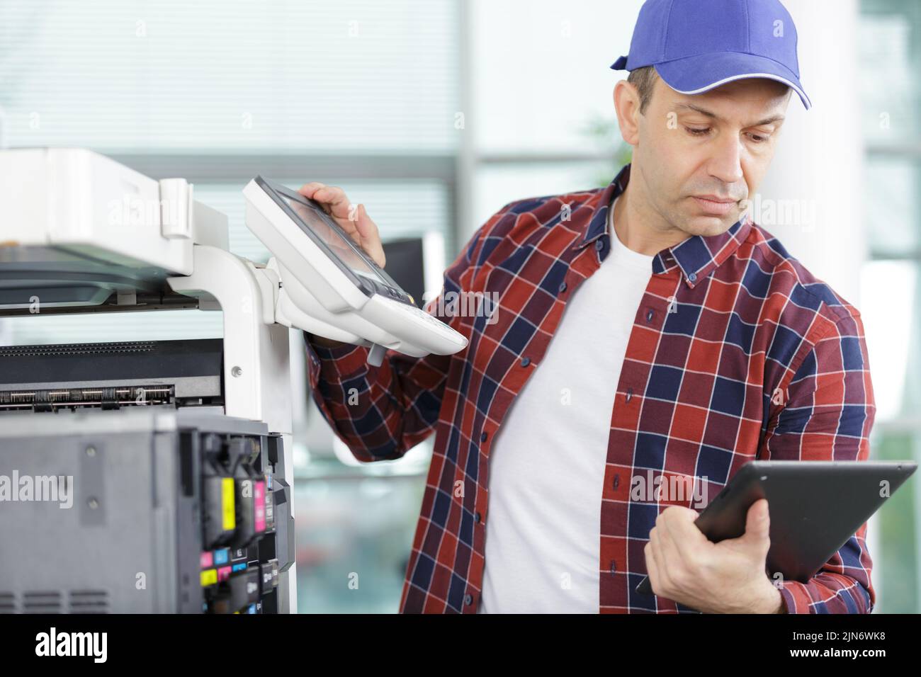technician using a tablet to fix a printer Stock Photo