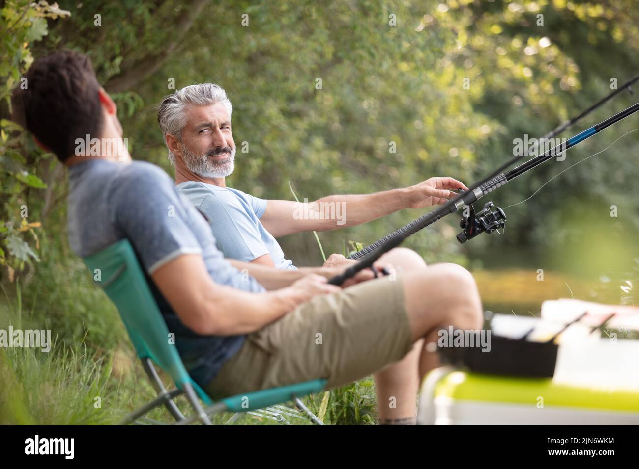 two fishermen with fishing rods catching fish Stock Photo