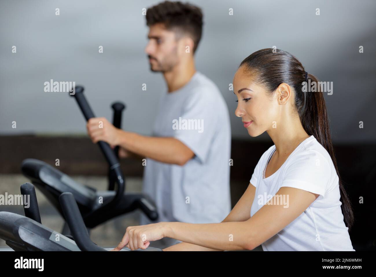 man and woman walking on treadmills in modern gym Stock Photo