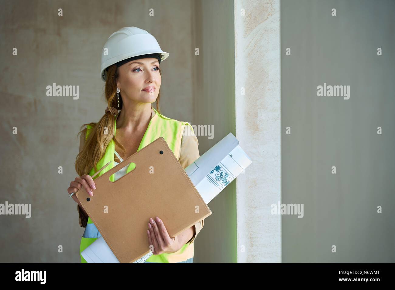 Woman realtor with folders and project stands in unfinished house Stock Photo