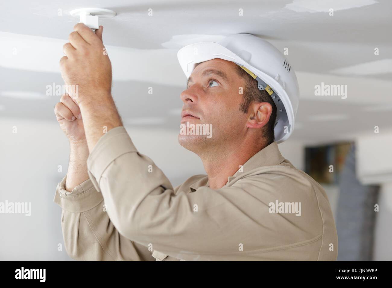 electrician working on ceiling light fitting Stock Photo