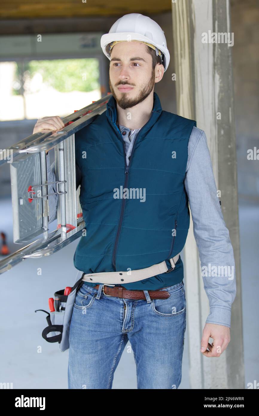 painter in jumpsuit carries a ladder Stock Photo Alamy