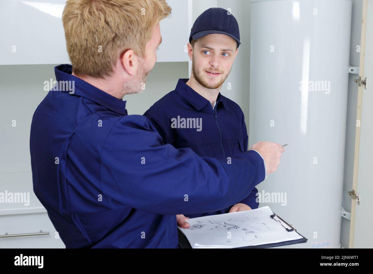 trainee plumber working on boiler with male engineer Stock Photo