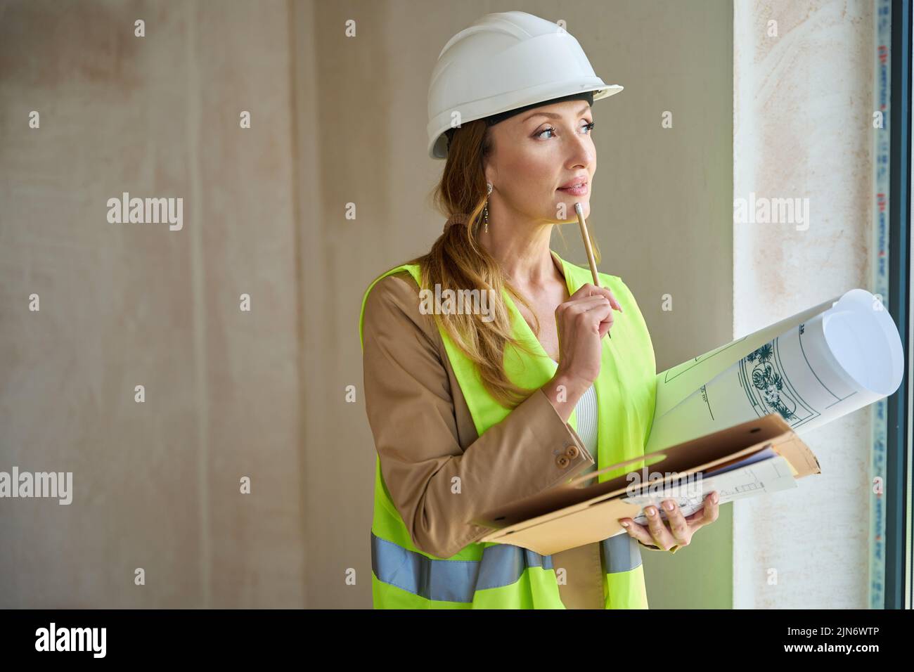 Thoughtful woman realtor holds pencil near her face Stock Photo