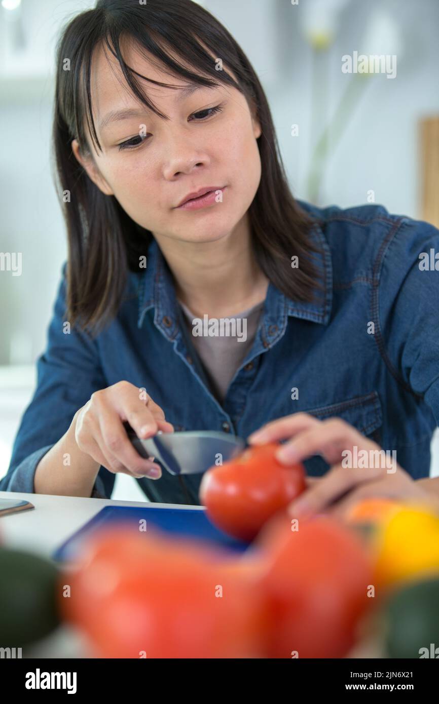 woman cuts tomatoes on a wooden board Stock Photo