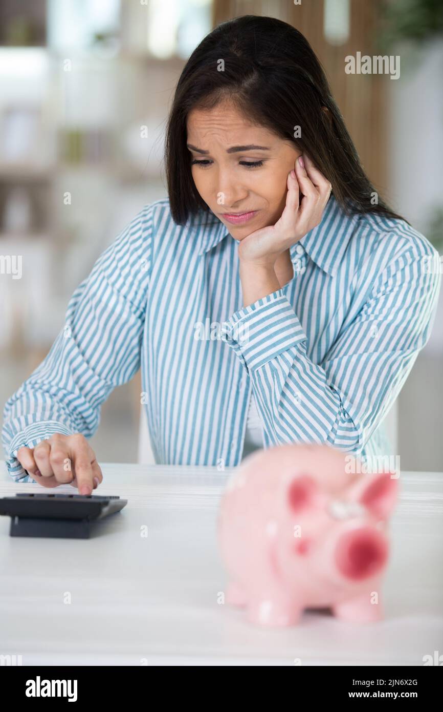 frustrated woman with calculator and piggybank Stock Photo