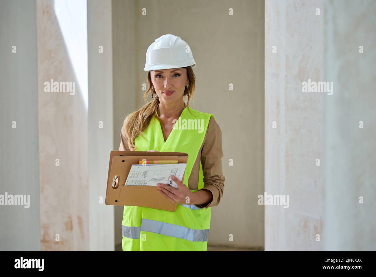Real estate manager in protective helmet takes notes in folder Stock Photo