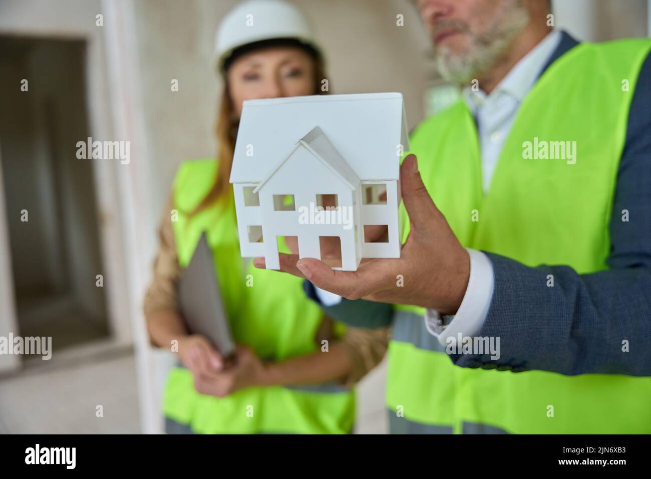 Foreman shows real estate manager a miniature house. Construction progress Stock Photo