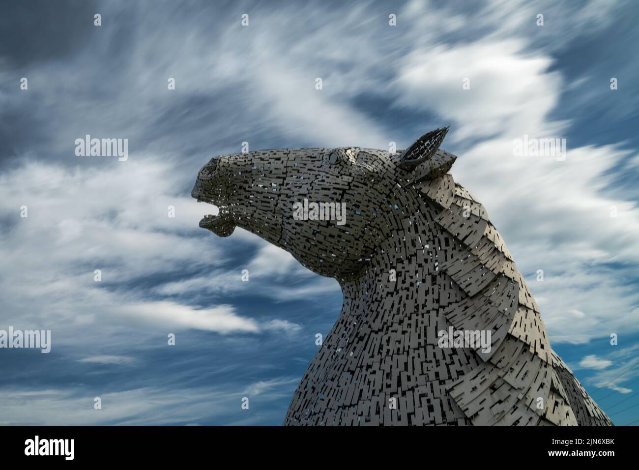 Falkirk, United Kingdom - 20 June, 2022: one of the Kelpies horse head sculptures with an expressive long exposure sky behind Stock Photo