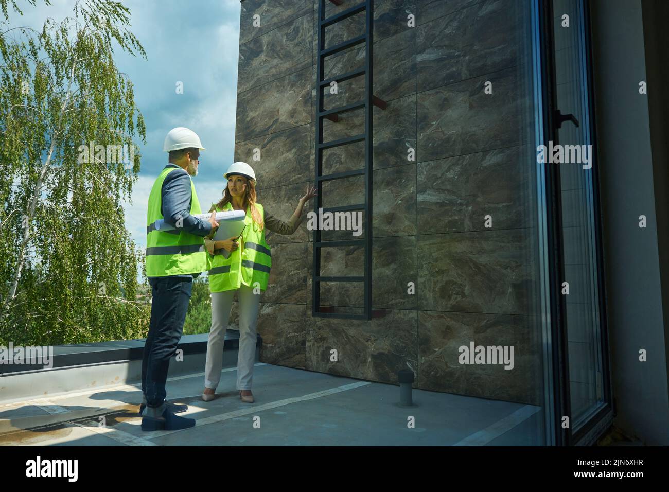 Manager in protective helmet is talking to foreman on balcony Stock Photo