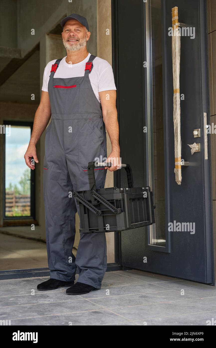 Portrait of smiling worker in overalls and with tool box Stock Photo