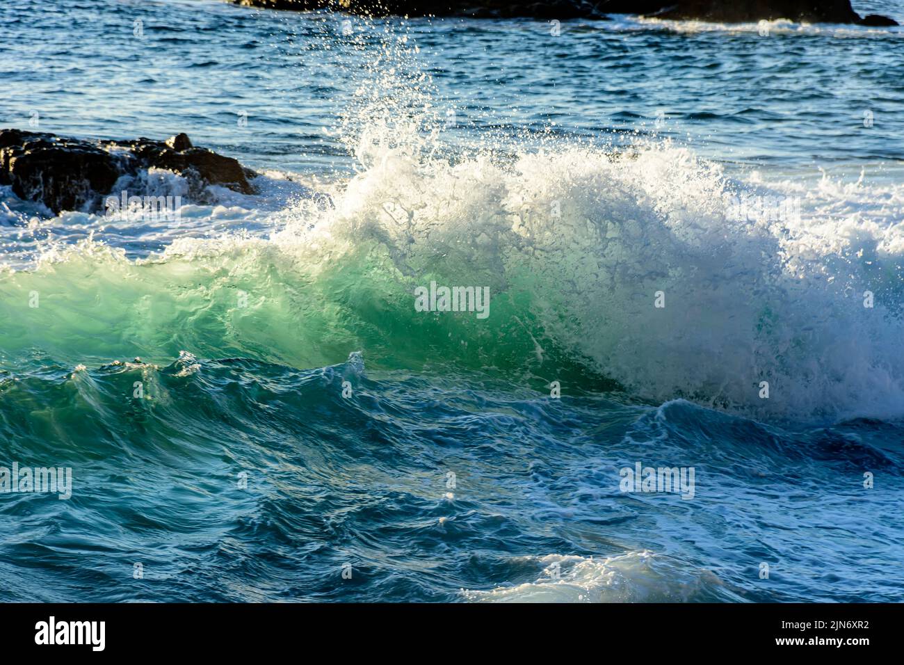 Small wave breaking with water spray released into the air in the sea of Salvador, Bahia Stock Photo