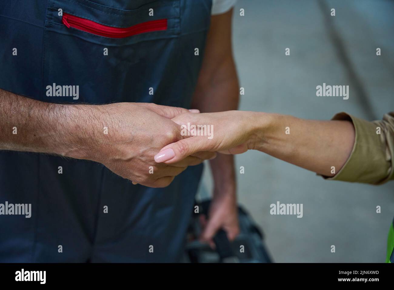 Female hand clasps male builder hand in overalls. Close up photo Stock Photo