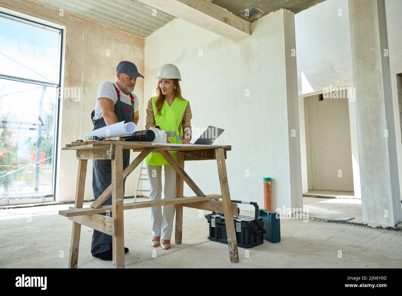 Realtor shows builder blueprints and laptop that lies on table Stock Photo