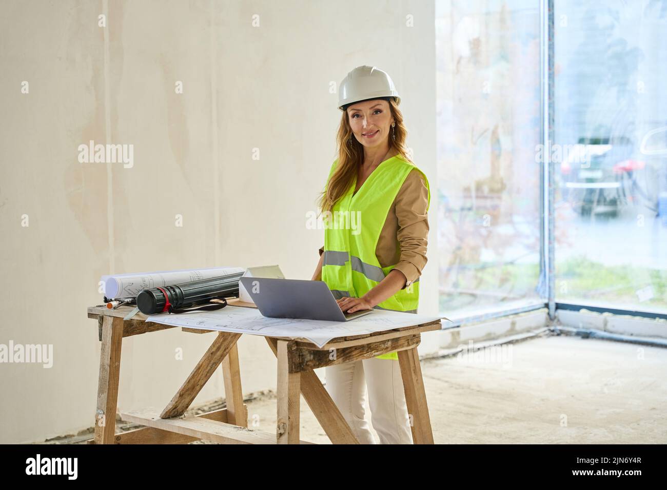 Real estate agent standing near table with laptop and blueprints Stock Photo