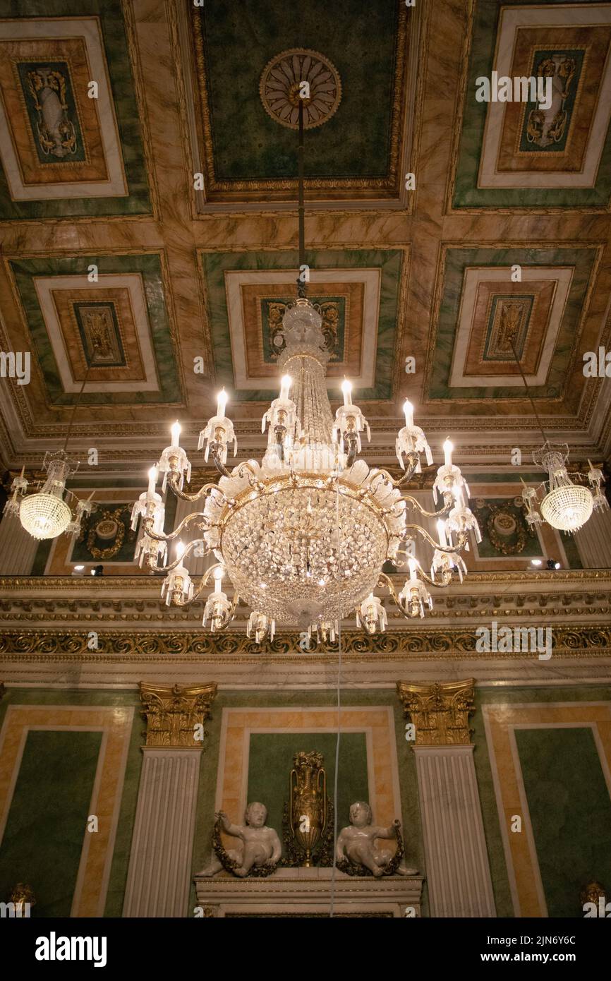 Brightly illuminated chandeliers with an antique decorative ceiling on the background, a vertical shot Stock Photo