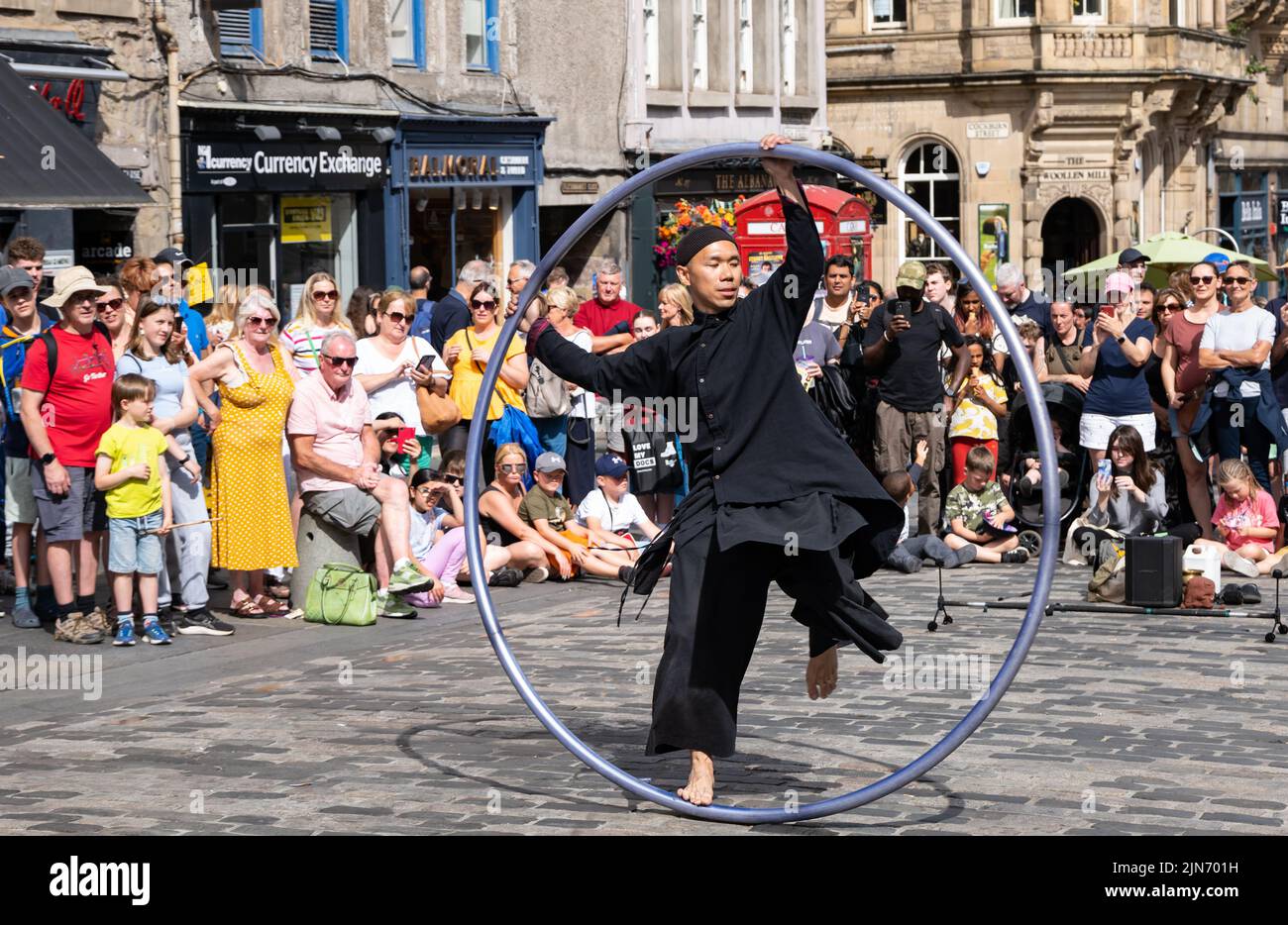 Royal Mile, Edinburgh, Scotland, UK, 9th August 2022. Edinburgh Festival Fringe street performer: a man performs acrobatic stunts on a cyr wheel for the crowd in the sunshine Stock Photo