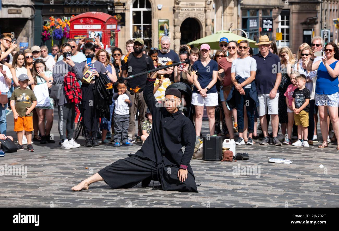 Royal Mile, Edinburgh, Scotland, UK, 9th August 2022. Edinburgh Festival Fringe street performer: a man performs for the crowd in the sunshine playing with fire. Credit: Sally Anderson/Alamy Live News Stock Photo