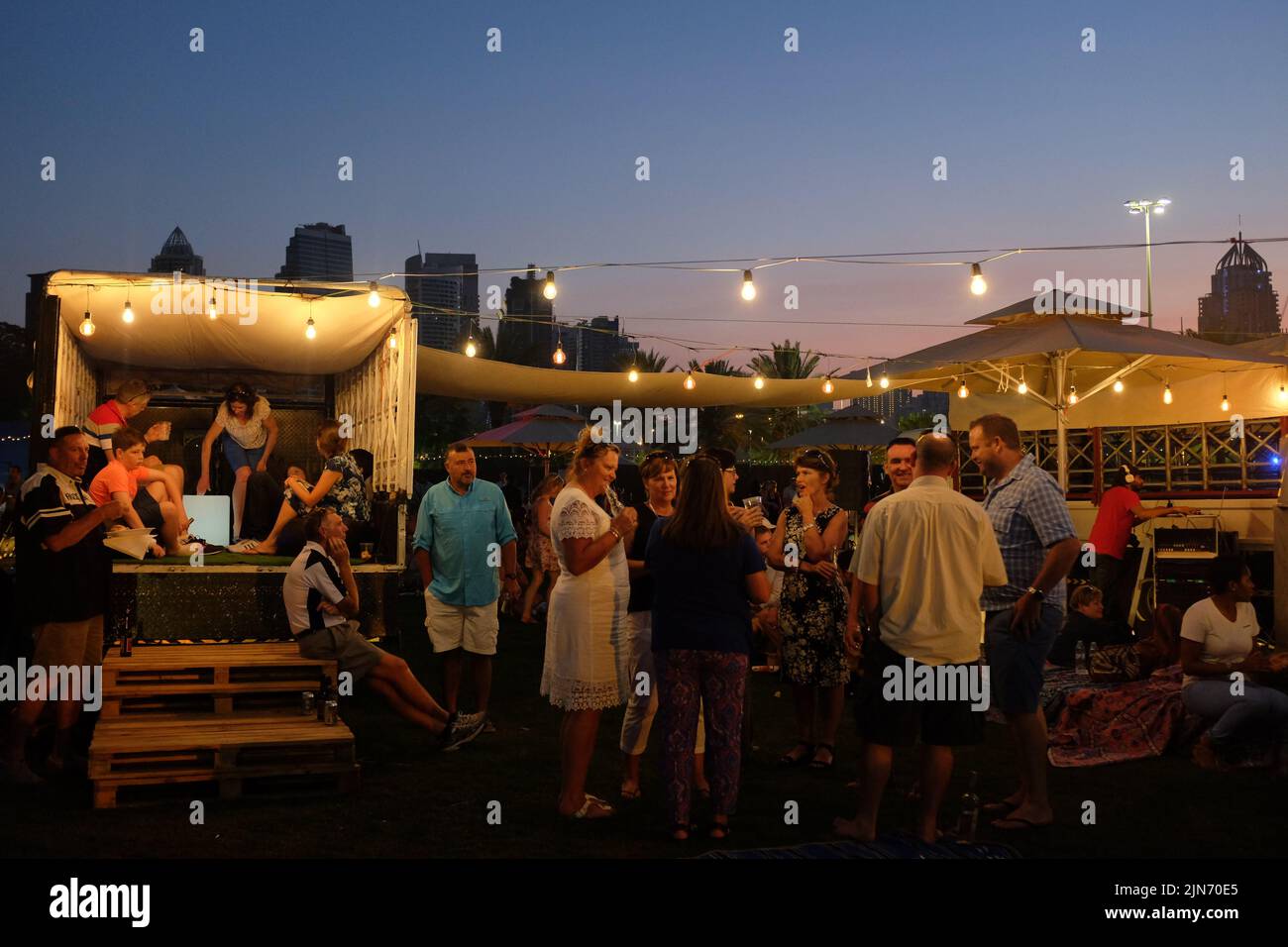 Dubai, United Arab Emirates - March 26, 2016: adults gather with drinks as the sun goes down at the Food Truck Jam in Emirates Golf Club. Stock Photo