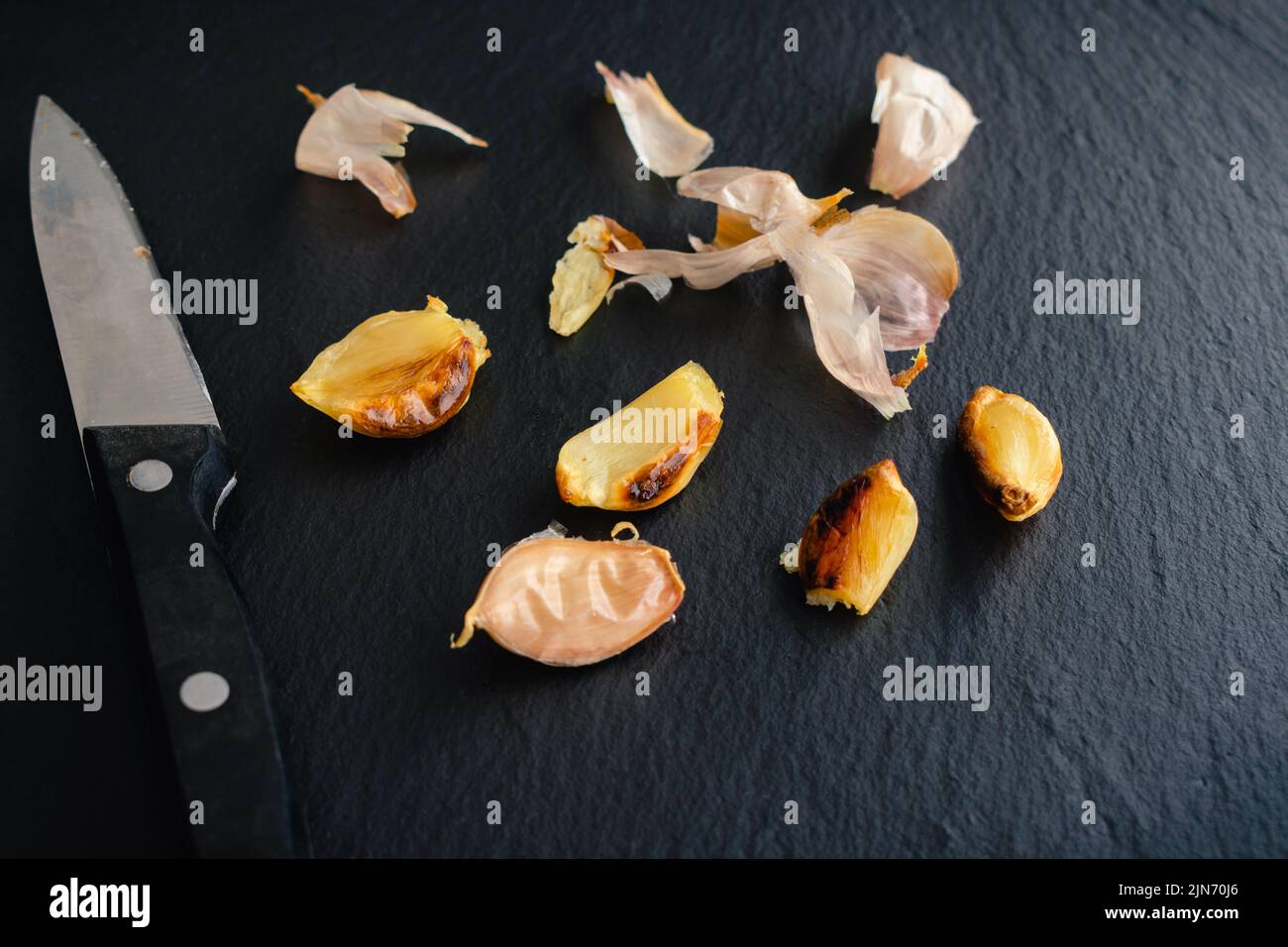 Roasted Garlic Cloves on a Dark Slate Stone Background Peeled and