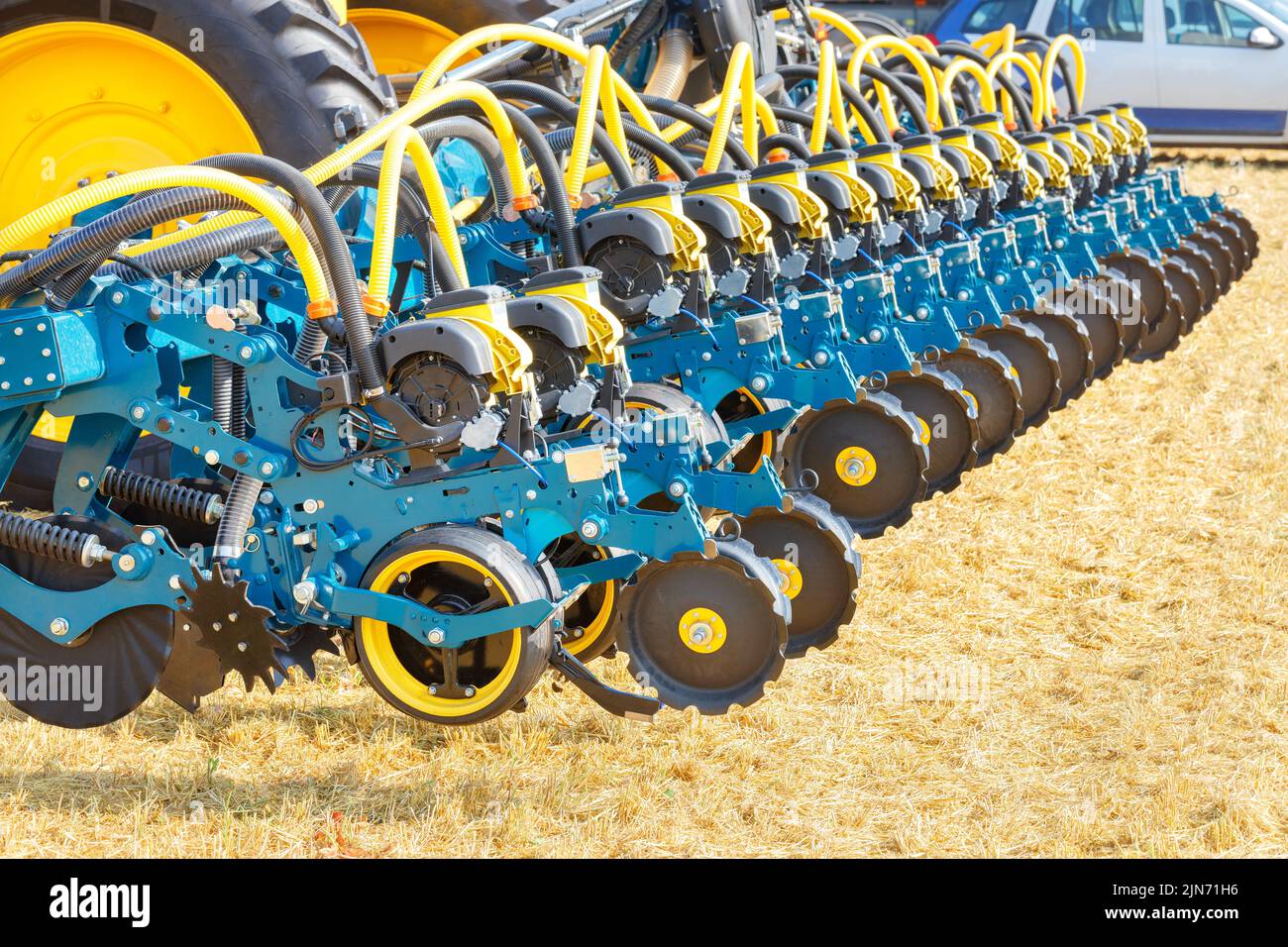 Multi row seeder with a pneumatic mechanism for even distribution and sowing of seeds against the backdrop of an agricultural field on a sunny day. Stock Photo