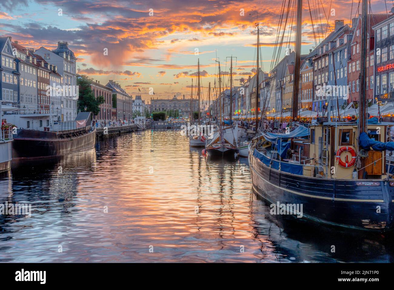 A beautiful shot of a famous tourist spot Nyhavn in Copenhagen with a waterscape and ducked boats Stock Photo