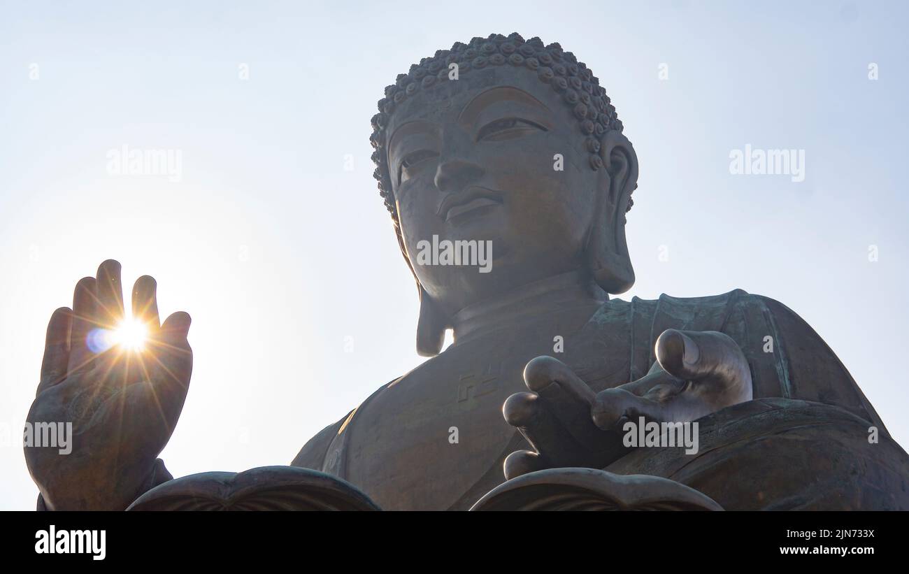 A low-angle shot of the sunlight glowing through the fingers of Buddha ...