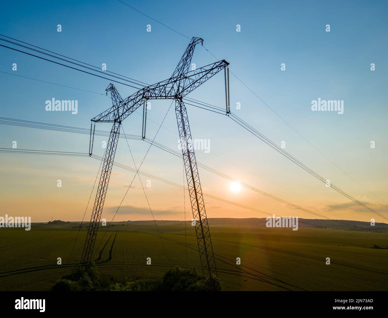 Dark silhouette of high voltage towers with electric power lines at ...