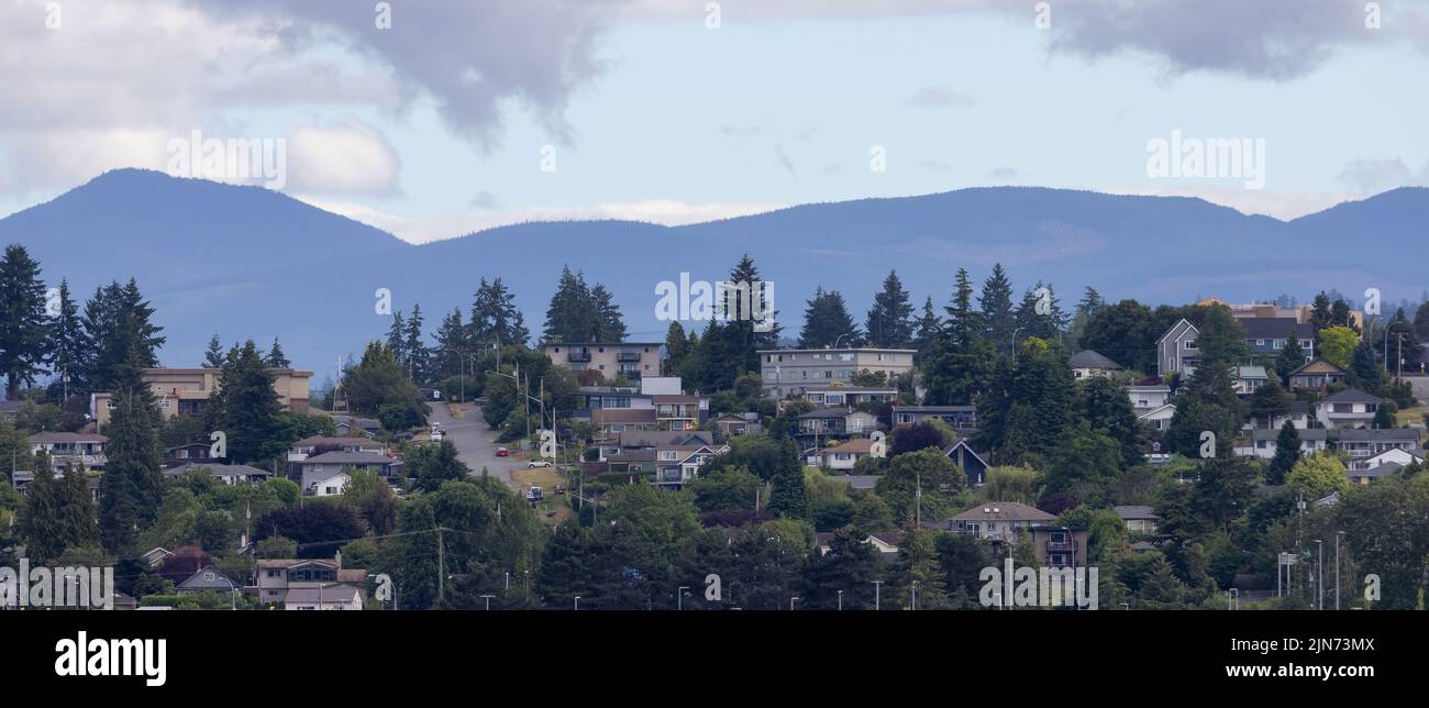 Homes by the water, surrounded by tees and mountains. Summer Season. Nanaimo Stock Photo