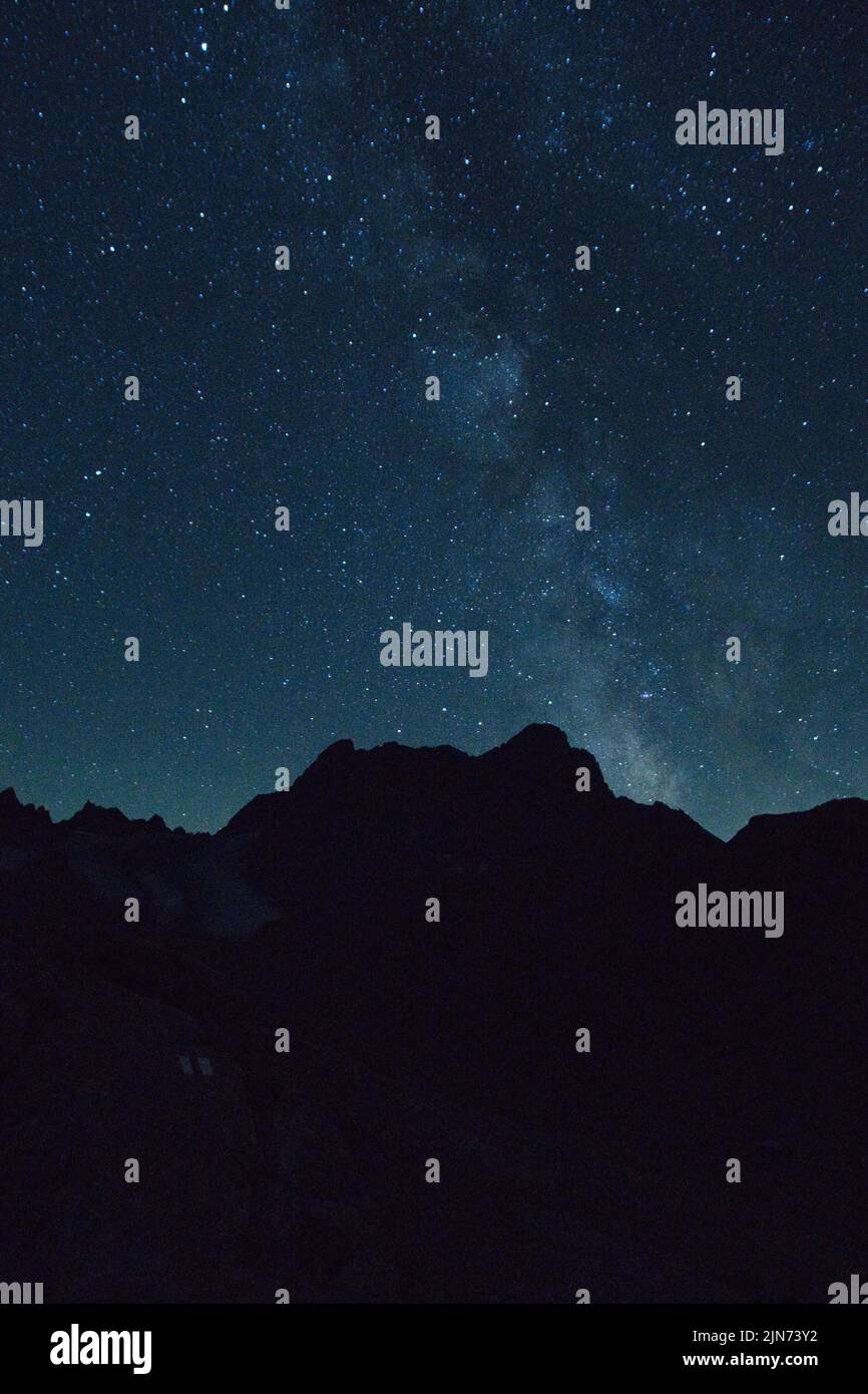 A vertical shot of mountain silhouettes and a beautiful night sky with ...