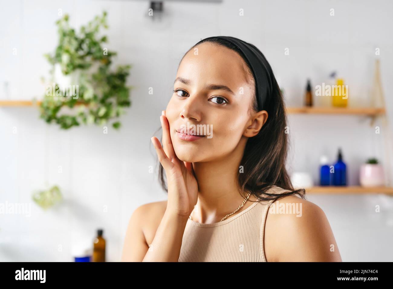 Close up portrait of young hispanic woman touching face with fingers. Wellness, cosmetics, skin care Stock Photo