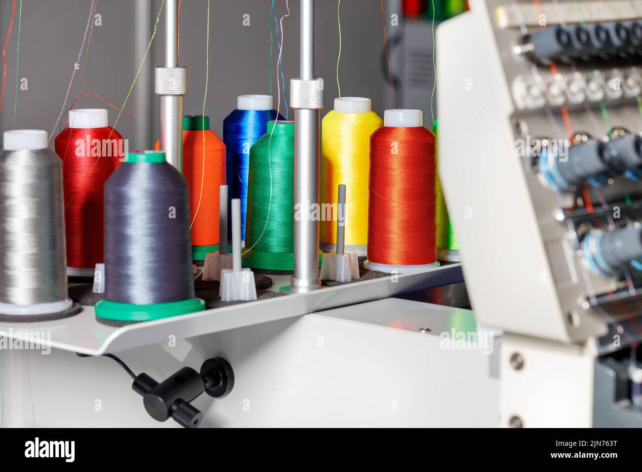 Spools of colored threads for industrial sewing and embroidery machines on a blurred background. Copy space. Closeup. Stock Photo