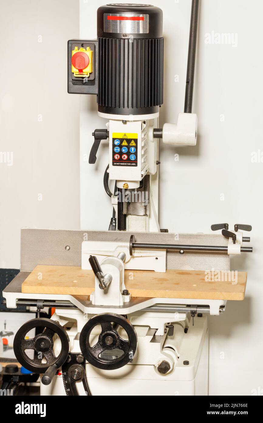 Closeup of an electric vertical milling machine with a powerful motor for processing wood parts in a workshop. Stock Photo