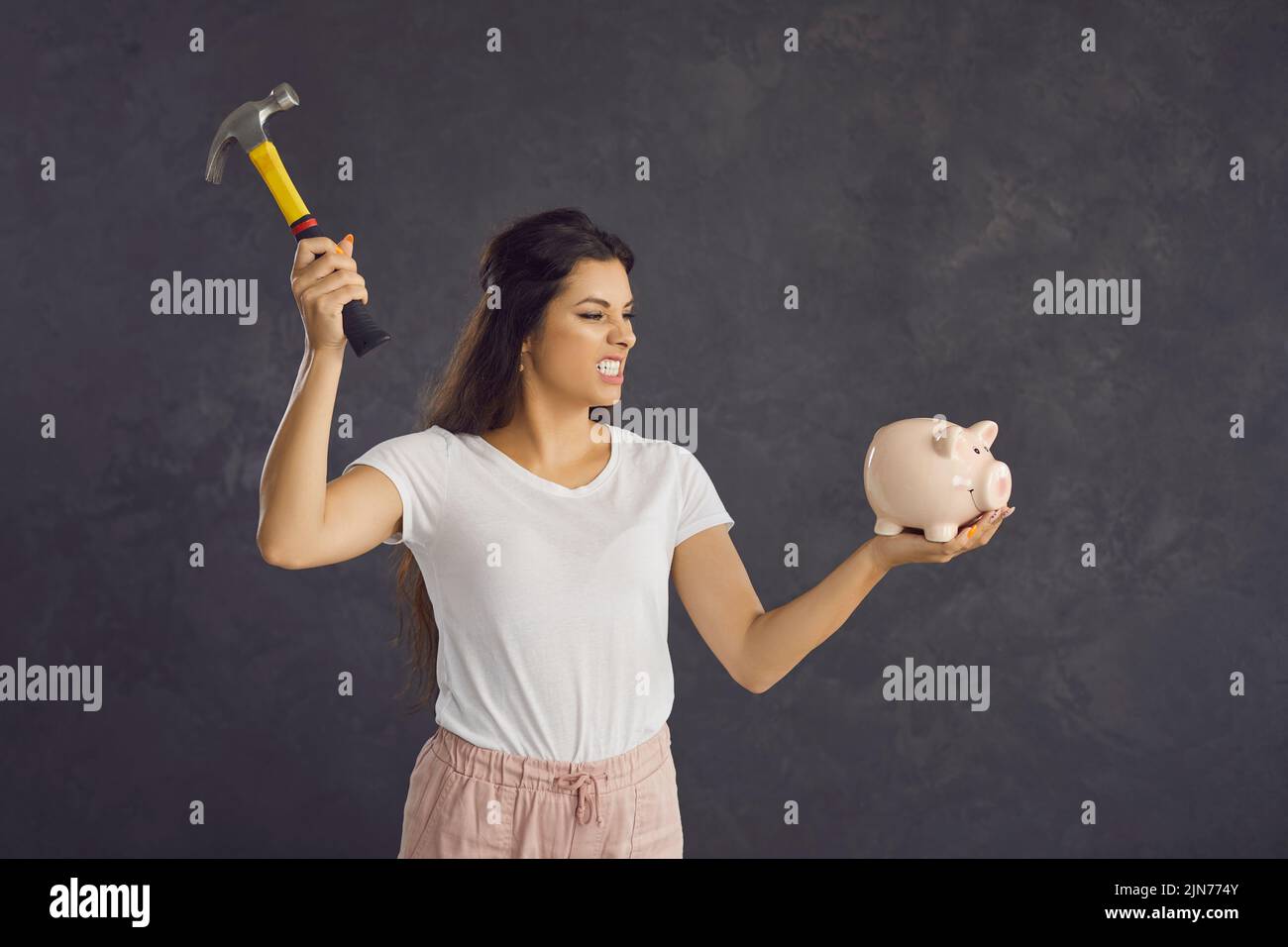 Furious woman break piggybank for money savings Stock Photo