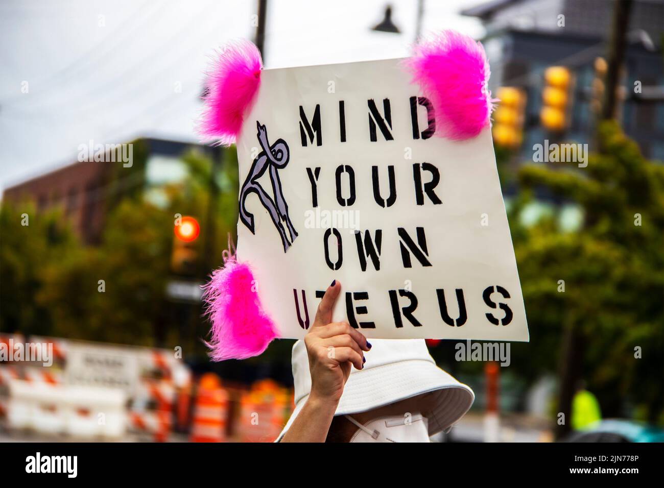 Woman in hat and mask at Reproductive Justice March holds up sign Mind Your Own Uterus Stock Photo