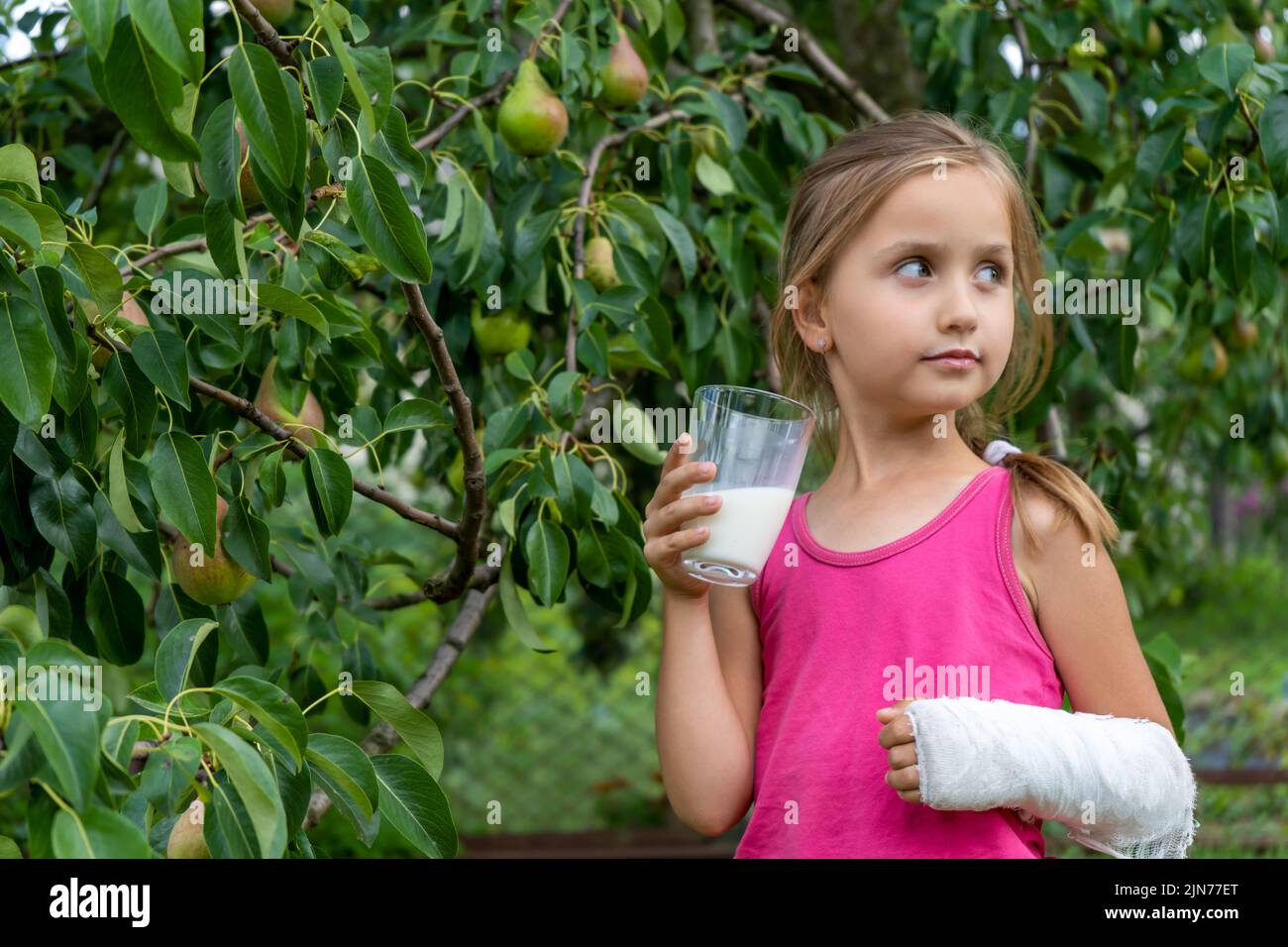 Cute little girl with a broken arm in a cast drink milk and enjoy