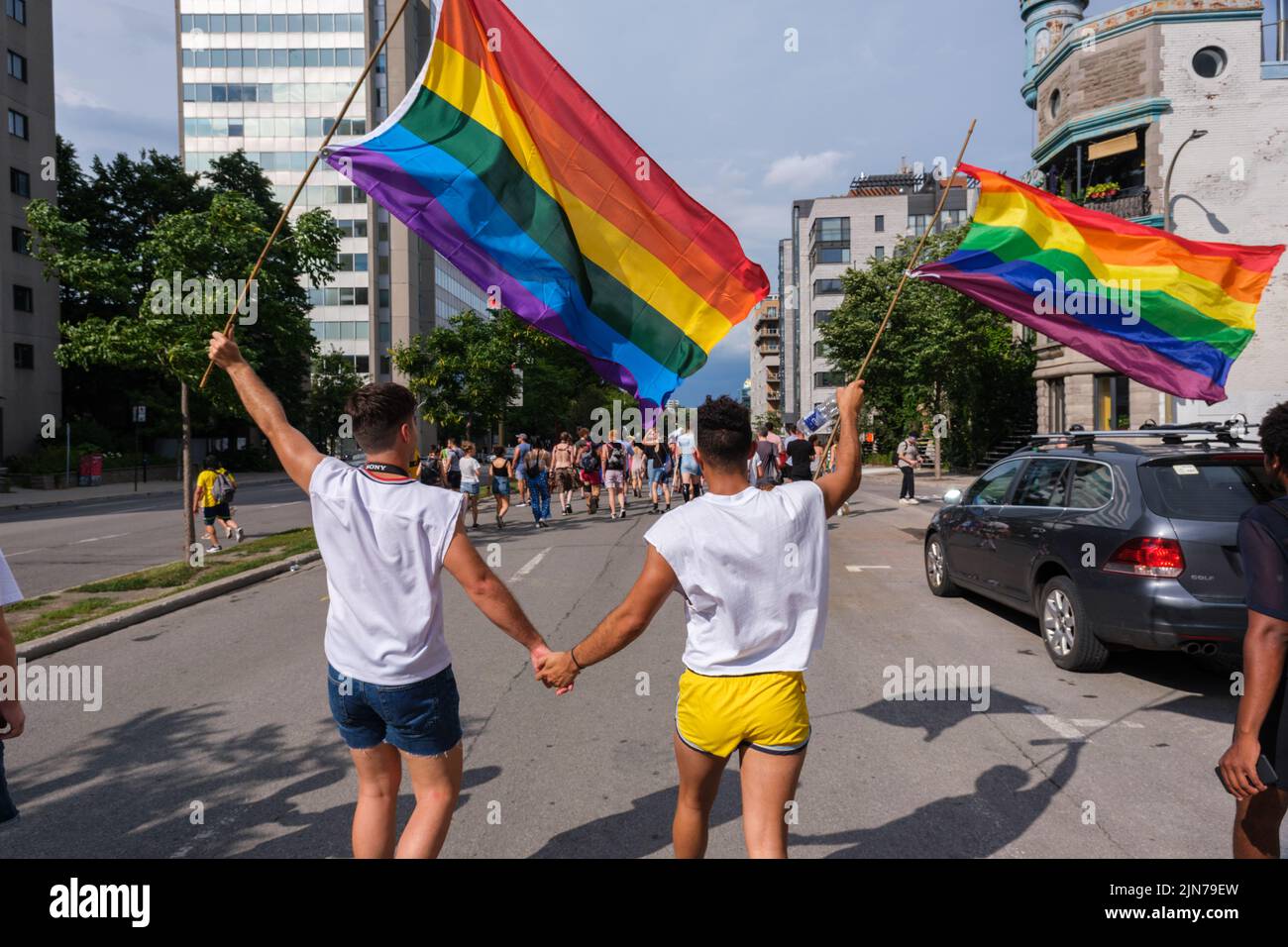 Montreal, CA - 7 August 2022: Two young men holding hands take part in spontaneous gay pride march after official pride parade was cancelled Stock Photo