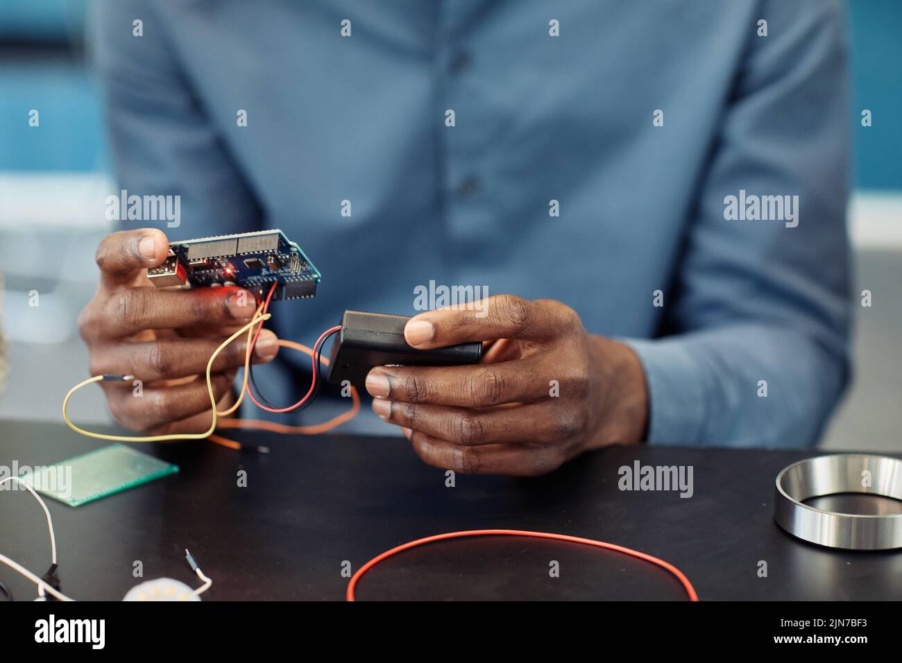 Close up of black young man holding circuit board while building robot, copy space Stock Photo