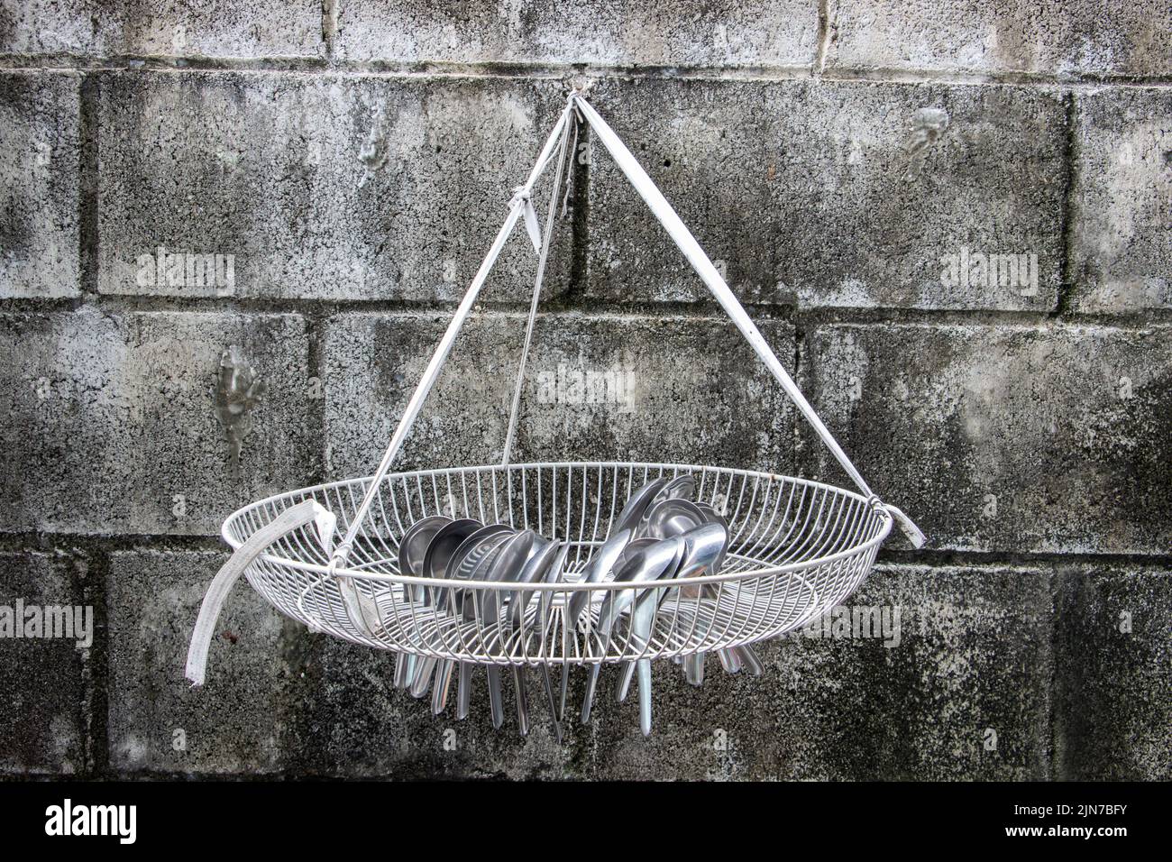 Aluminum spoons are dried in a grate drip tray hang on the wall Stock