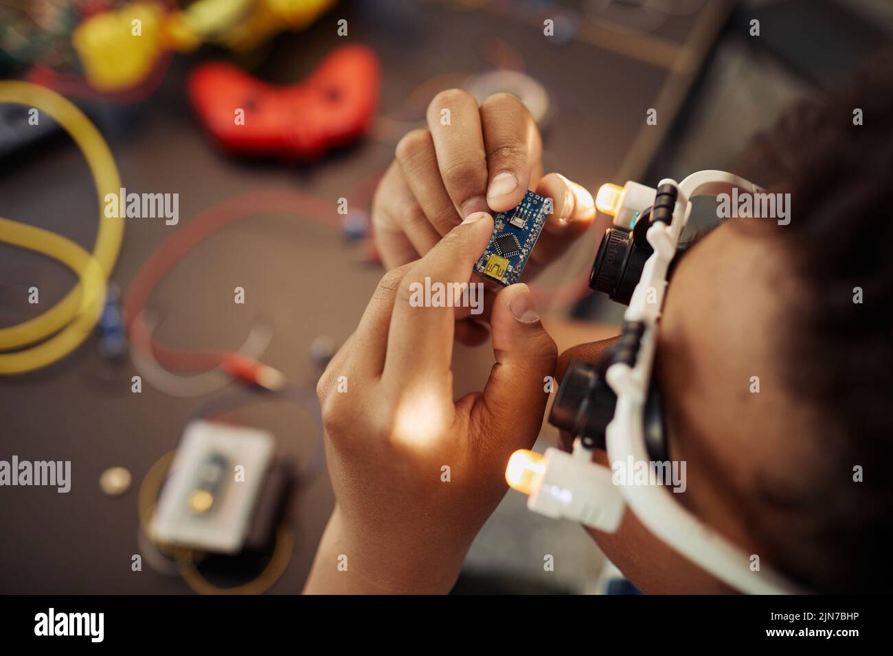 Top view closeup of black boy holding circuit board while building robot, copy space Stock Photo