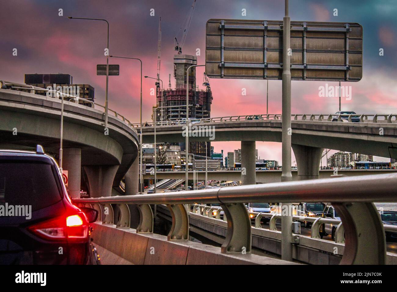 Sunset in the city - driving tangled traffic-filled roads at rush hour under colorful sky - Brisbane Australia Stock Photo