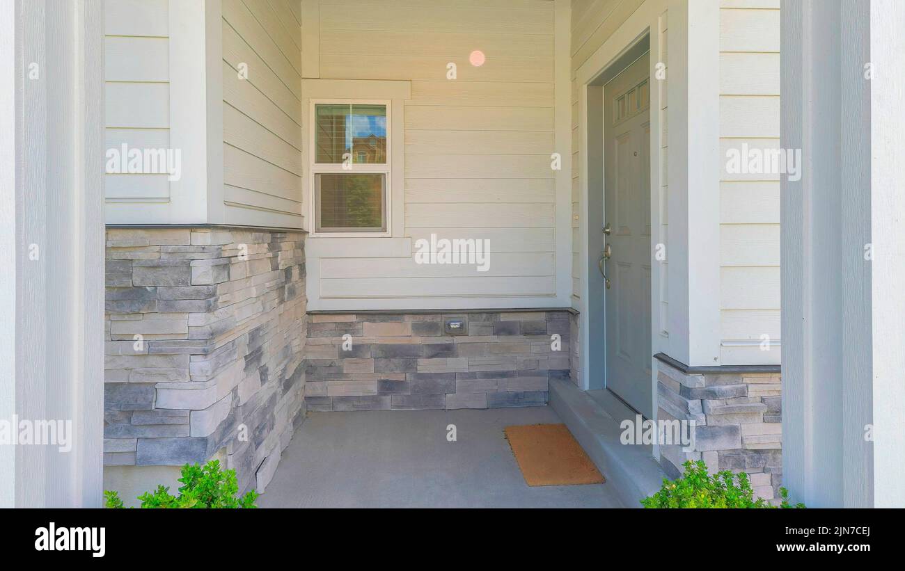 Panorama Entrance of a house with gray door on the side and two potted ...