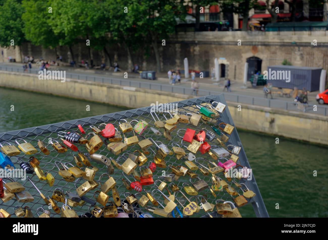 Paris, France - May 26, 2022: Padlocks signifying love attached to Pont au Change bridge over River Seine with riverbank blurred in background Stock Photo