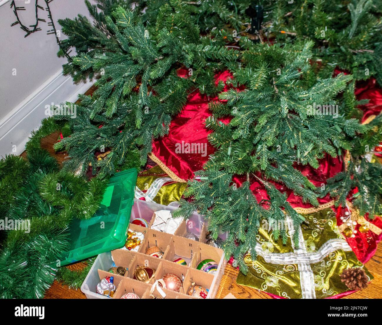 Taking the tree down after the holidays - dismantling an artifical tree with lights and vintage ornaments in a storage box. Stock Photo