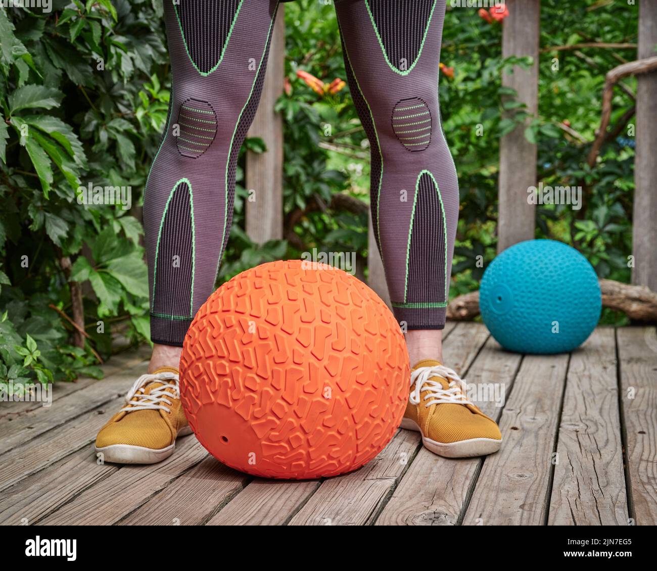 male wearing compression sleeves is exercising with a heavy slam ball