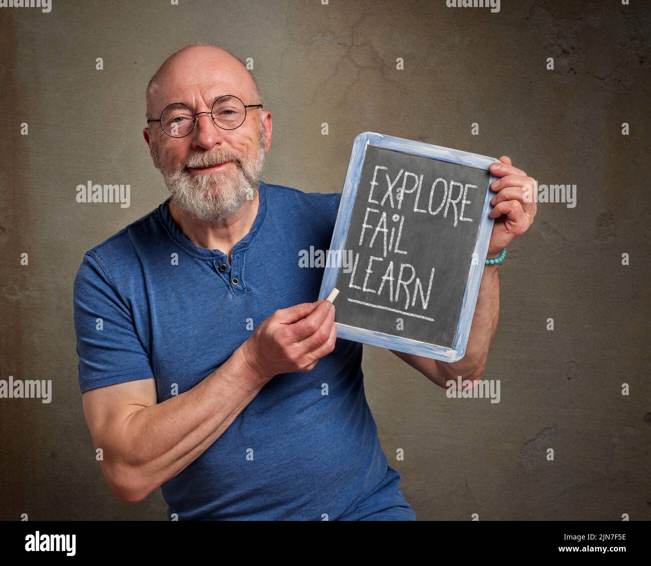 explore, fail and learn - inspirational note, white chalk writing on a slate blackboard held by a senior man, teacher or mentor, challenge, success an Stock Photo