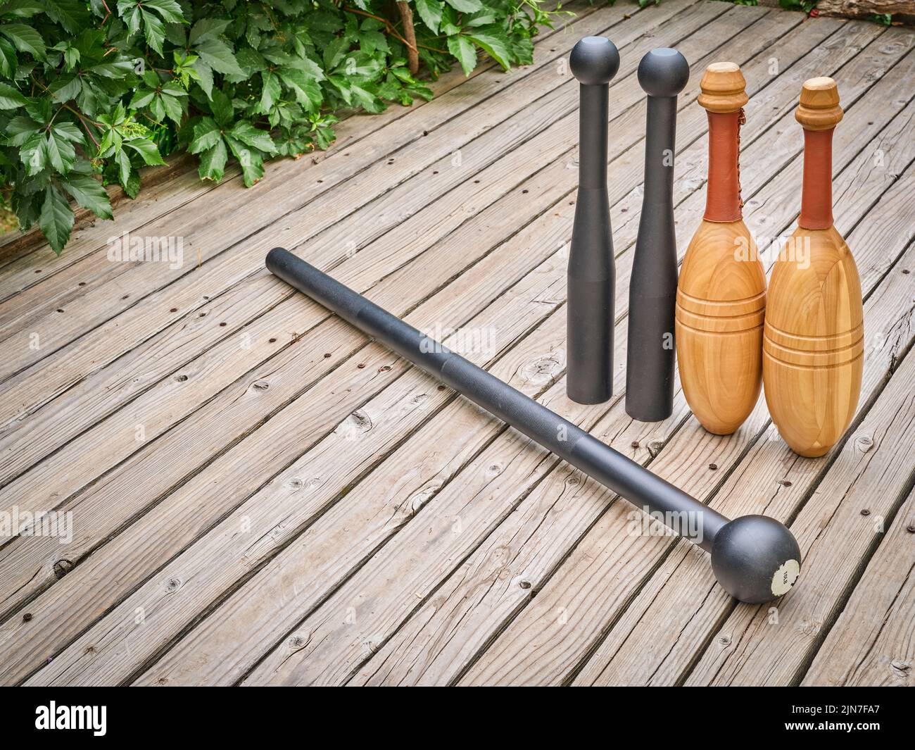 steel mace, steel clubs and wooden Indian clubs on a backyard deck, functional fitness concept Stock Photo