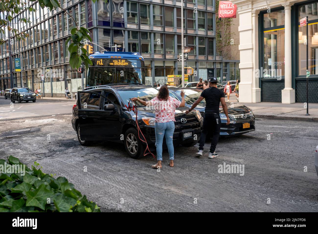 A woman holds up traffic while she gets a jump from a livery driver in Soho in New York on Saturday, July 30, 2022.  (© Richard B. Levine) Stock Photo