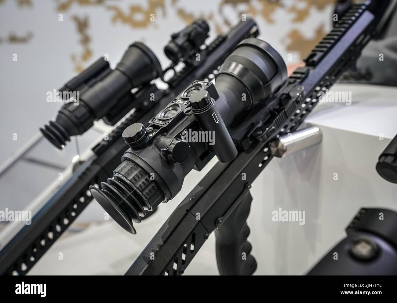 Black shooting scope optics mounted on metal bar displayed at weapons